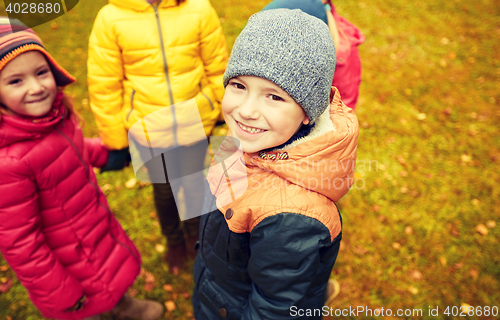 Image of children holding hands and playing in autumn park