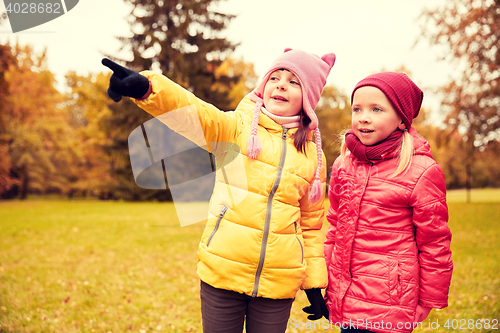 Image of happy little girls pointing finger in autumn park