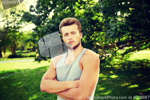 Image of sporty young man with crossed arms at summer park