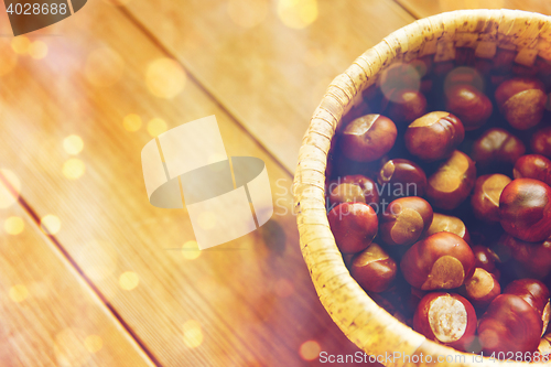 Image of close up of chestnuts in basket on wooden table