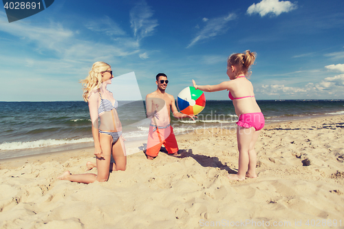 Image of happy family playing with inflatable ball on beach