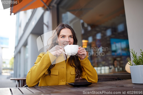 Image of happy woman drinking cocoa at city street cafe