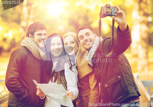 Image of group of friends with photo camera in autumn park