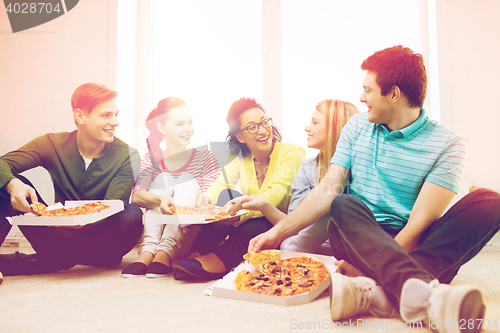 Image of five smiling teenagers eating pizza at home