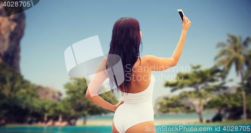 Image of young woman taking selfie with smartphone on beach