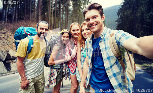 Image of friends with backpack taking selfie in wood