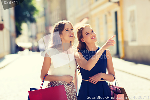 Image of happy women with shopping bags in city