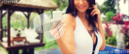 Image of woman taking selfie with smartphone over bungalow