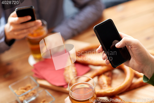 Image of close up of hands with smartphones and beer at bar
