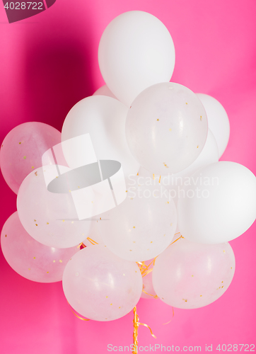 Image of close up of white helium balloons over pink