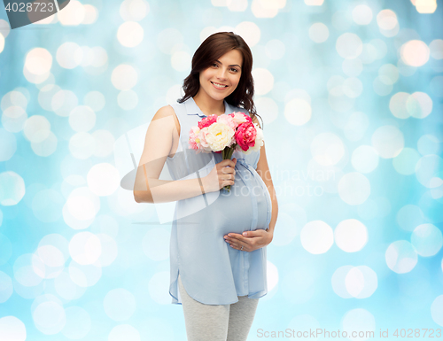 Image of happy pregnant woman with flowers touching belly