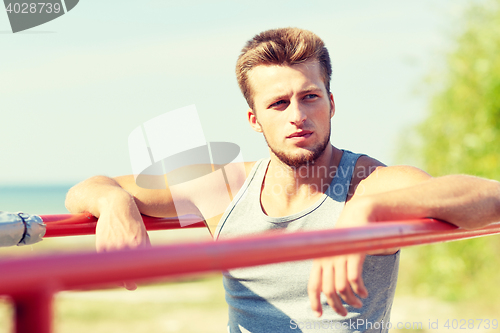 Image of young man exercising on parallel bars outdoors