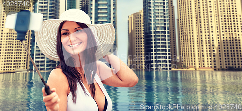 Image of woman taking selfie with smartphone over city pool