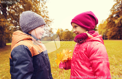Image of little boy giving autumn maple leaves to girl