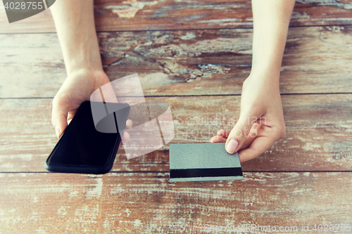 Image of close up of hands with smart phone and credit card