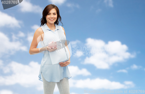 Image of happy pregnant woman with piggybank