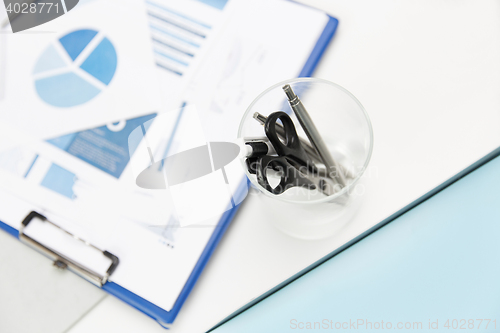 Image of close up of cup with scissors and pens at office