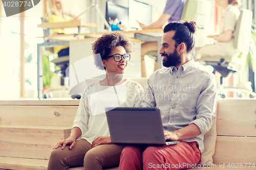 Image of happy creative team with laptop in office