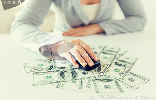 Image of close up of hand with computer mouse on money