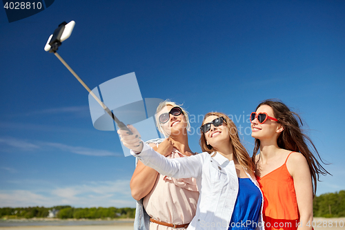 Image of group of smiling women taking selfie on beach