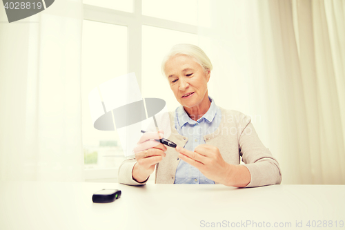 Image of senior woman with glucometer checking blood sugar