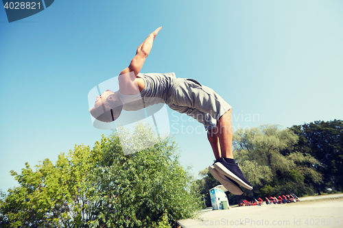 Image of sporty young man jumping in summer park