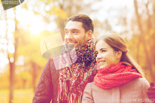 Image of smiling couple hugging on bridge in autumn park