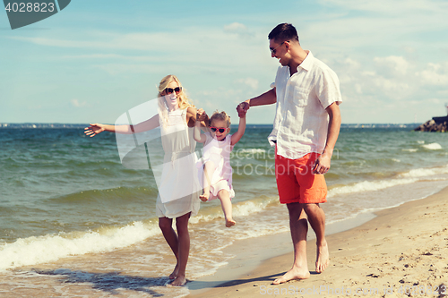 Image of happy family in sunglasses walking on summer beach