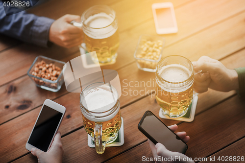 Image of close up of hands with smartphones and beer at bar