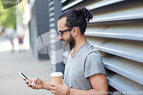 Image of man with coffee texting on smartphone in city