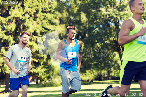 Image of happy young sportsmen racing wit badge numbers