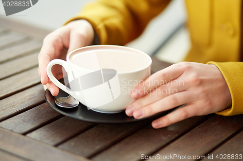 Image of close up of woman with cocoa cup at street cafe