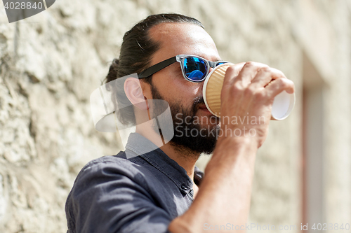 Image of man drinking coffee from paper cup on street