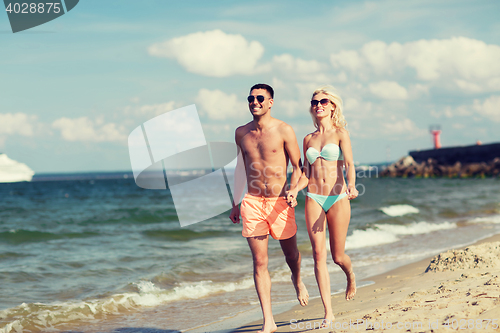 Image of happy couple in swimwear running on summer beach