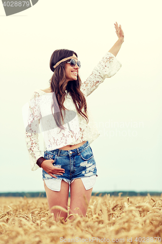 Image of smiling hippie woman on cereal field waving hand