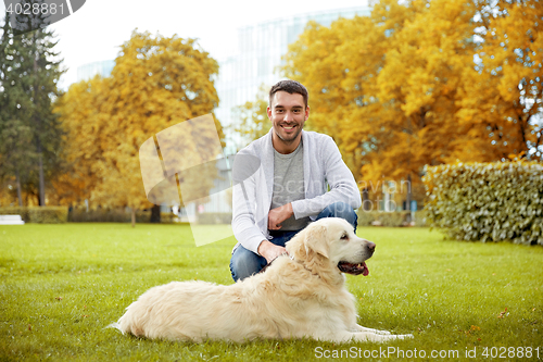 Image of happy man with labrador dog in autumn city park