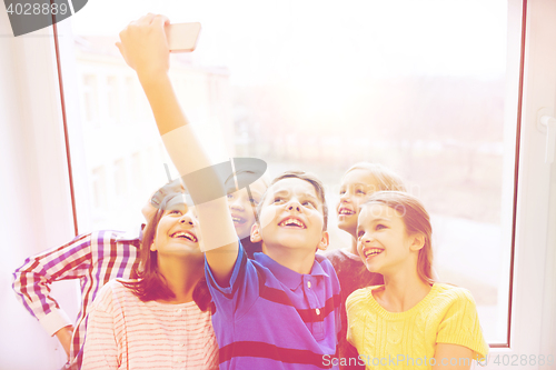 Image of group of school kids taking selfie with smartphone