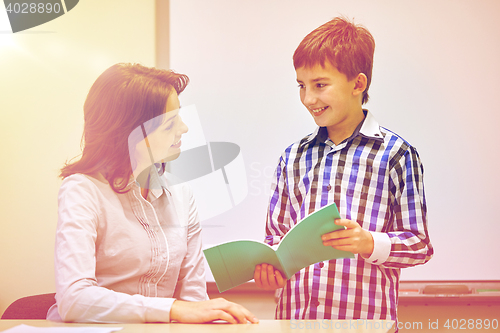 Image of school boy with notebook and teacher in classroom