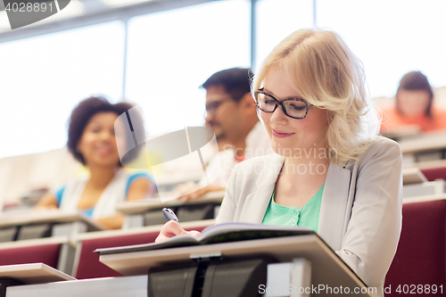 Image of student girl writing to notebook in lecture hall