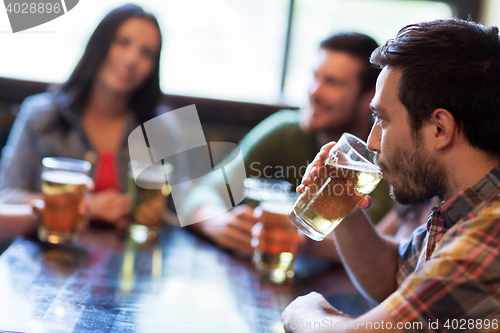 Image of happy friends drinking beer at bar or pub