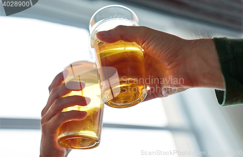 Image of close up of hands clinking beer glasses at pub