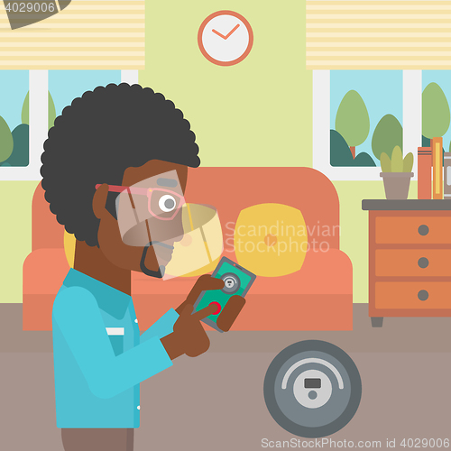 Image of Man controlling vacuum cleaner with smartphone.