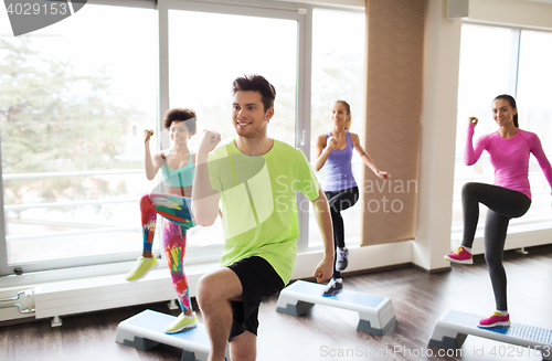 Image of group of people working out with steppers in gym