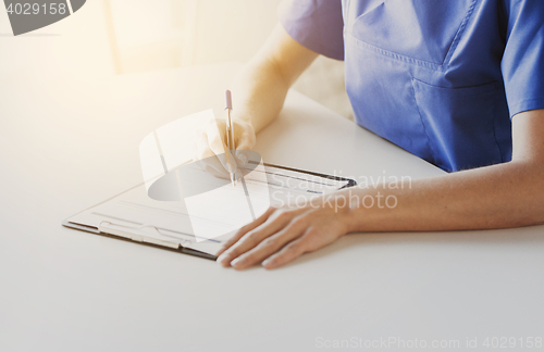 Image of close up of doctor or nurse writing to clipboard