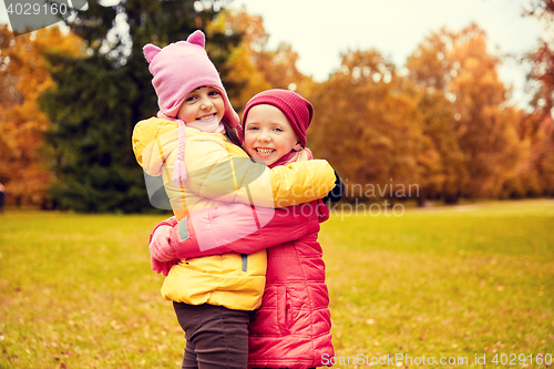 Image of two happy little girls hugging in autumn park