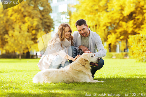 Image of happy couple with labrador dog in autumn city park