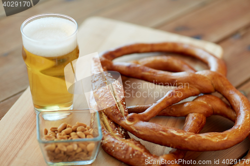 Image of close up of beer, pretzels and peanuts on table