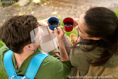 Image of happy couple with backpacks and tea cups in nature
