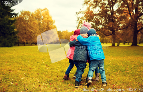 Image of group of happy children hugging in autumn park