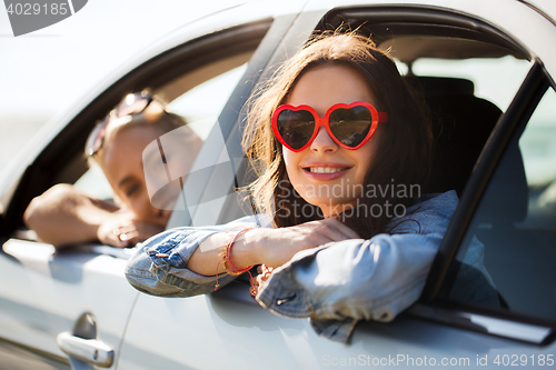 Image of happy teenage girls or women in car at seaside